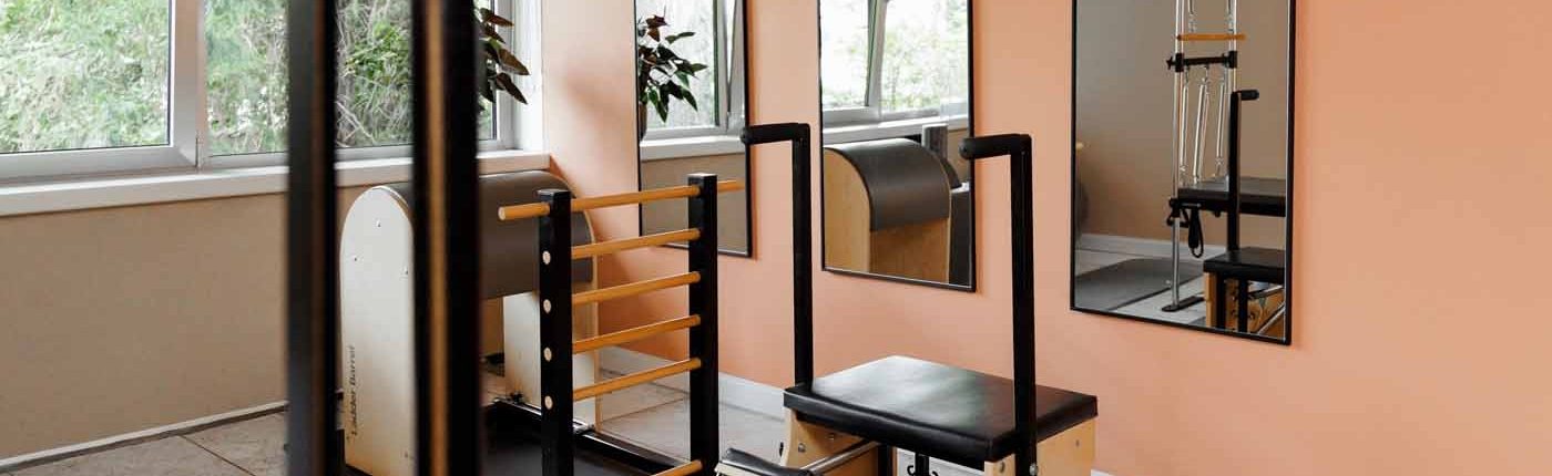 Pilates-Raum Heller Pilates-Raum mit mehreren Holzgeräten, Spiegeln und Gymnastikmatten.