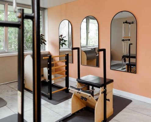 Pilates-Raum Heller Pilates-Raum mit mehreren Holzgeräten, Spiegeln und Gymnastikmatten.